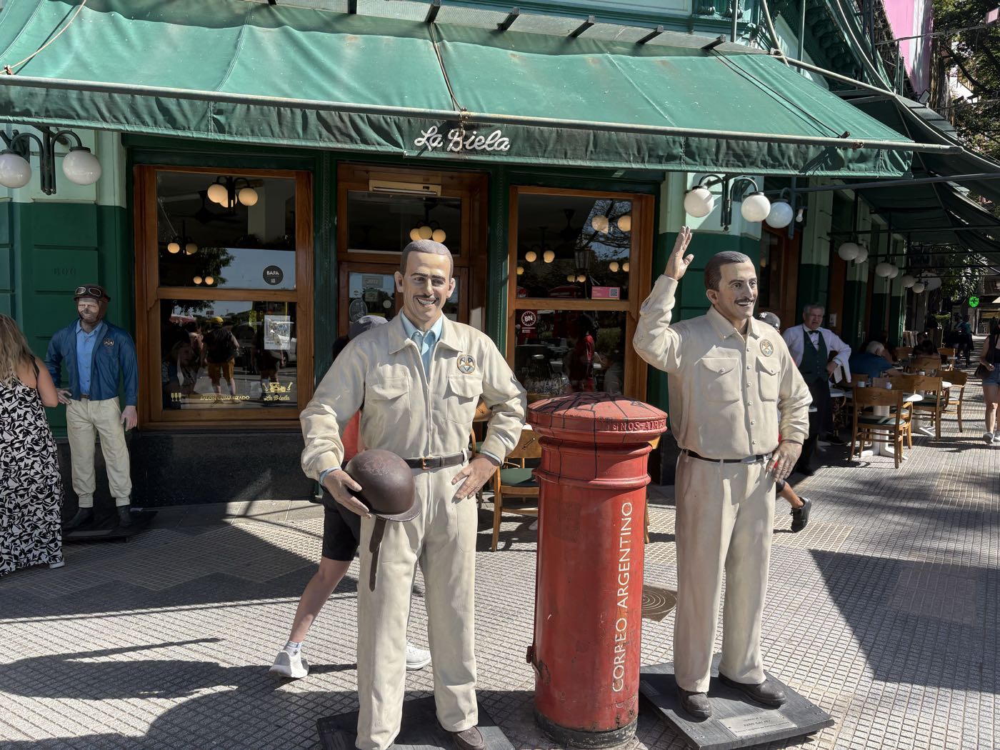 Life-size statues of two men in racing overalls outside Café La Biela