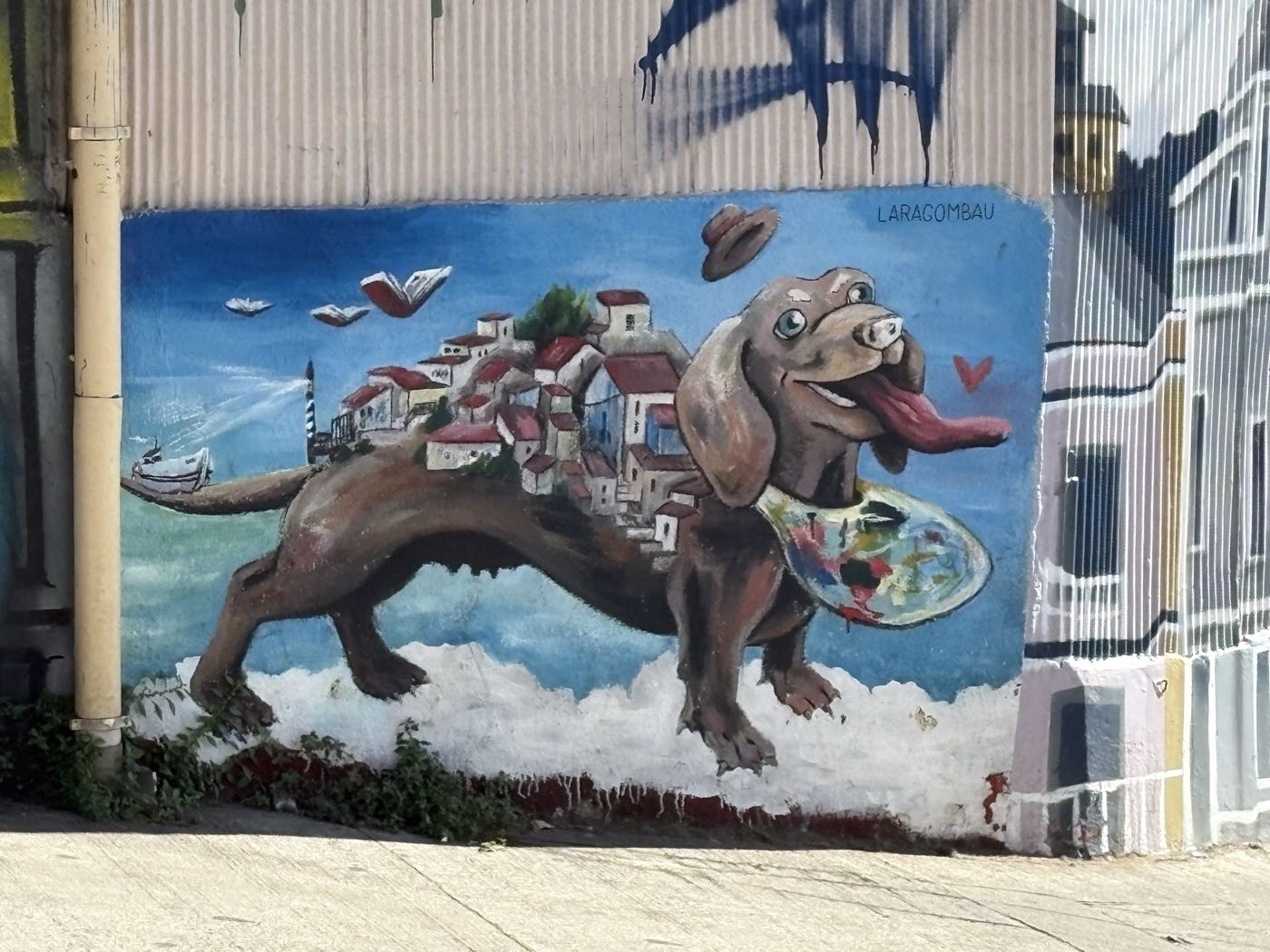 A mural of a dachshund carrying a hillside town on its back