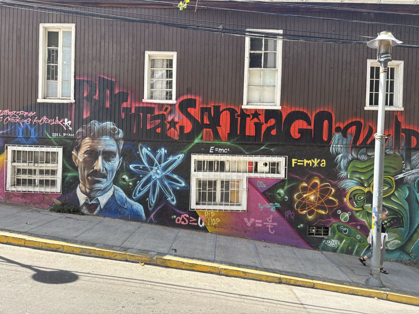 A mural with a portrait and physics formulas painted across a house front